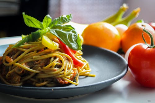 Pasta With Vegetable Dish on Gray Plate Beside Tomato Fruit